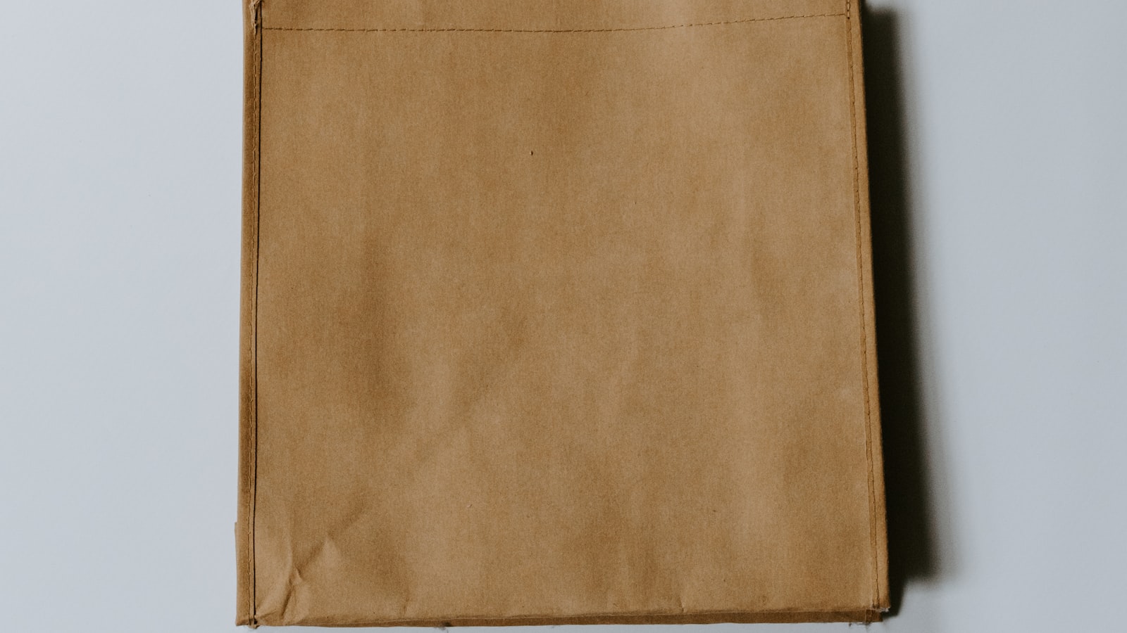 A beginner sewing at a wooden table with fabric, thread and scissors nearby